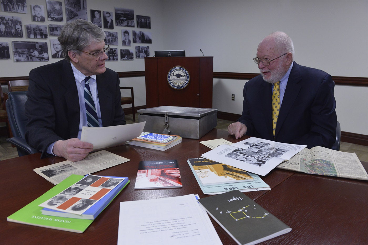 Jerry Parker sitting with Michael McElroy at a table discussing the items found in the time capsule.