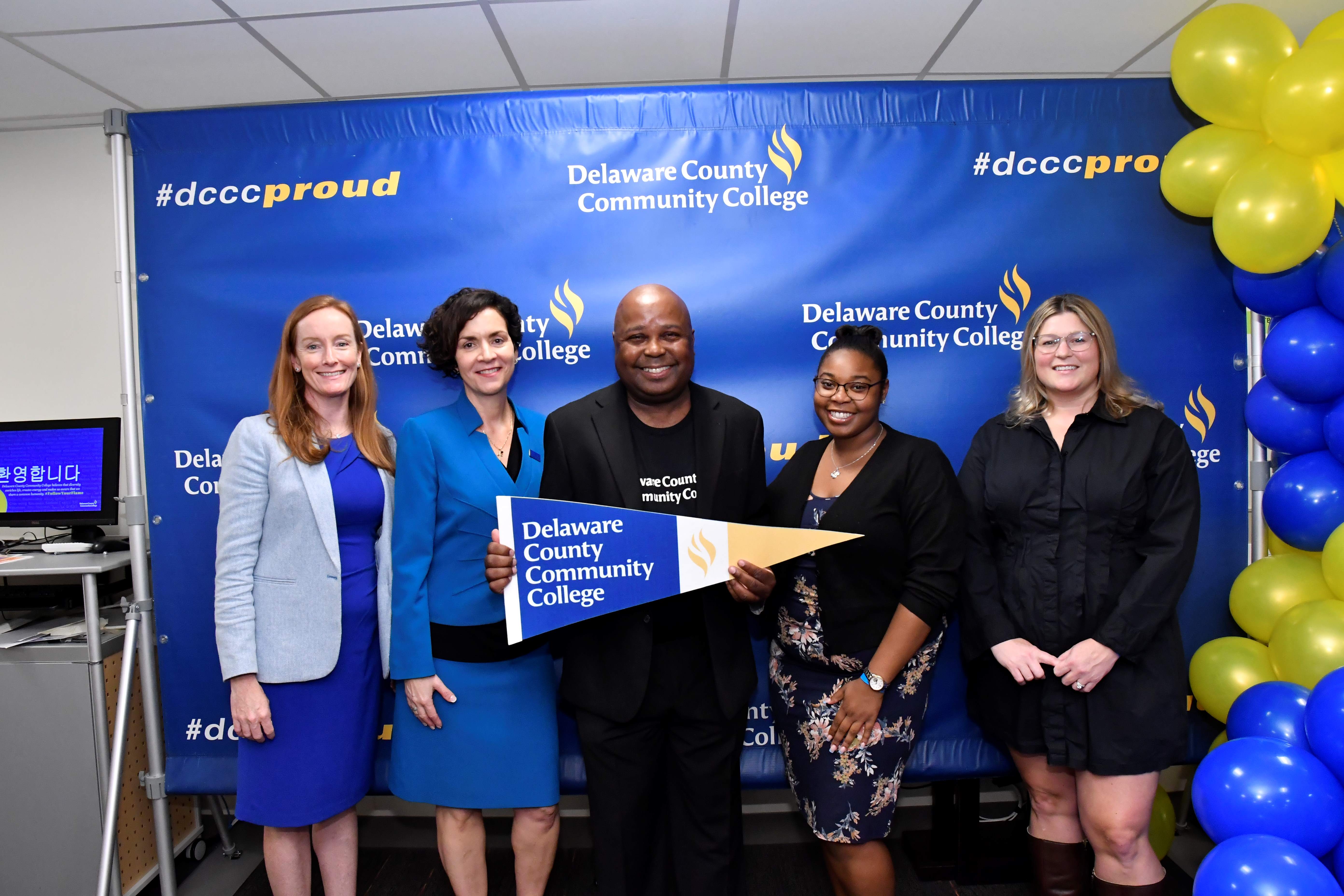 Laura Chisholm, Dr. Cronin and Dr. Mickens in front of DCCC backdrop