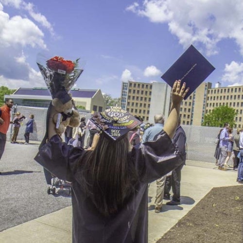 Grad holds up flowers and diploma